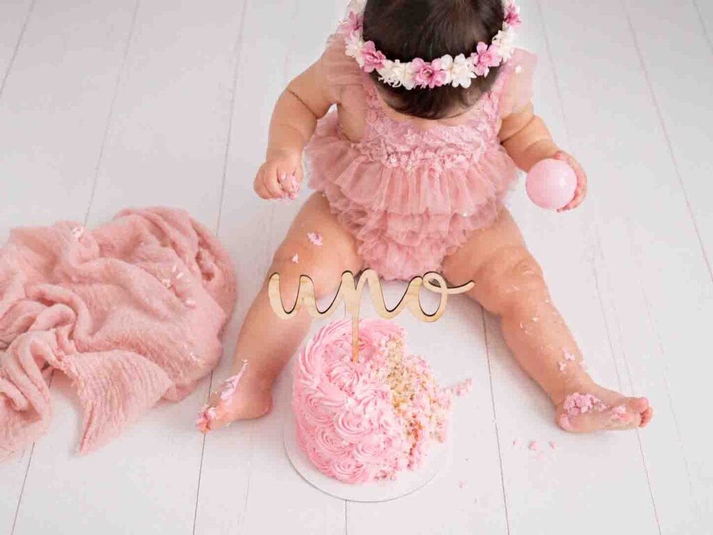 Bebé en sesión smash cake rosa con pastel rosa en estudio fotográfico