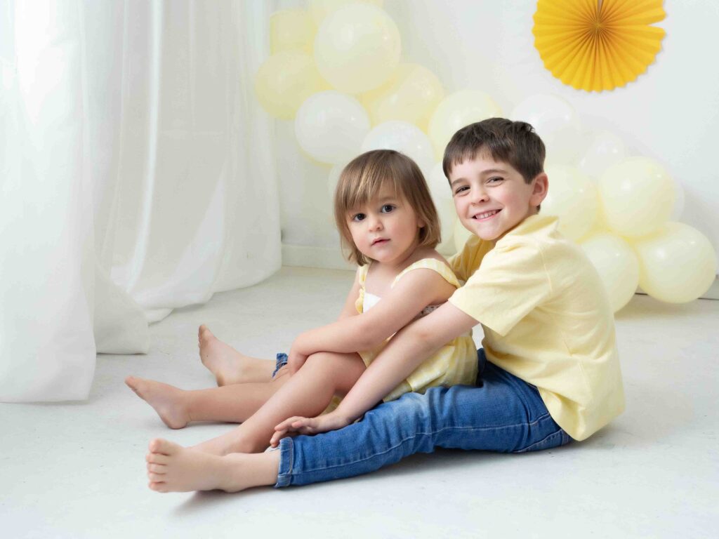 Niño abrazando a su hermana pequeña en una sesión smash cake
