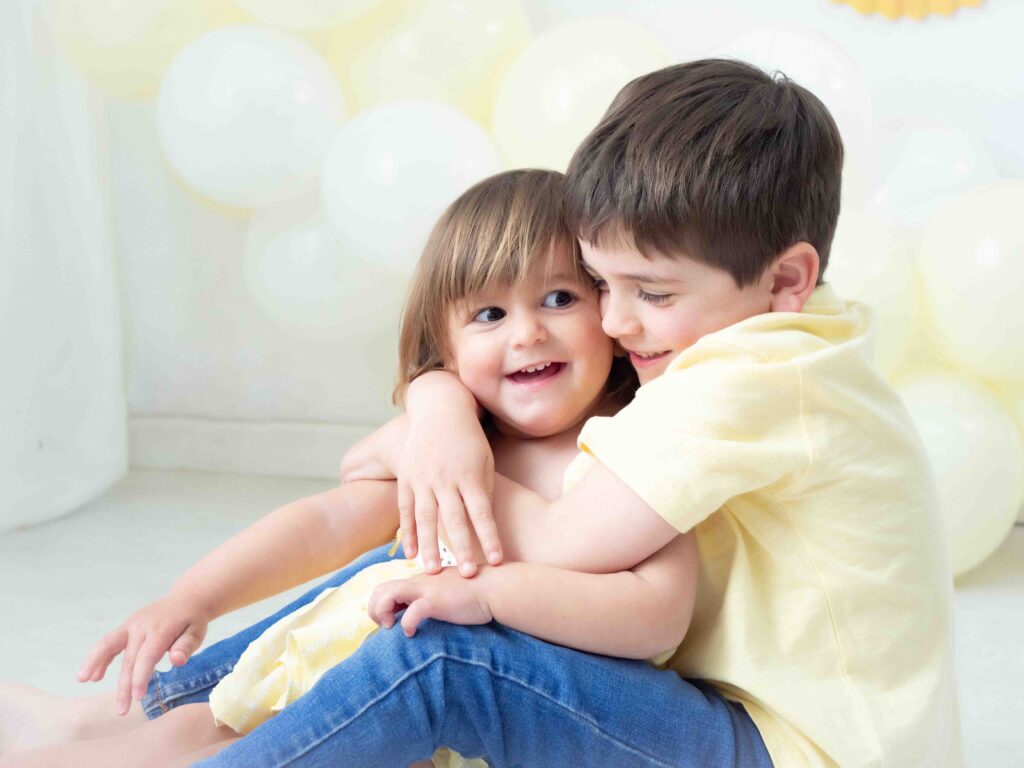 Hermanos de 2 y 5 años abrazándose durante una sesión de cumpleaños infantil