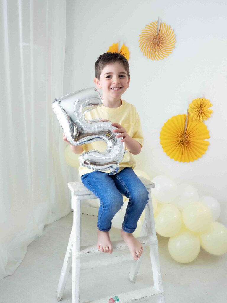 Niño celebrando su quinto cumpleaños en sesión de fotos infantil
